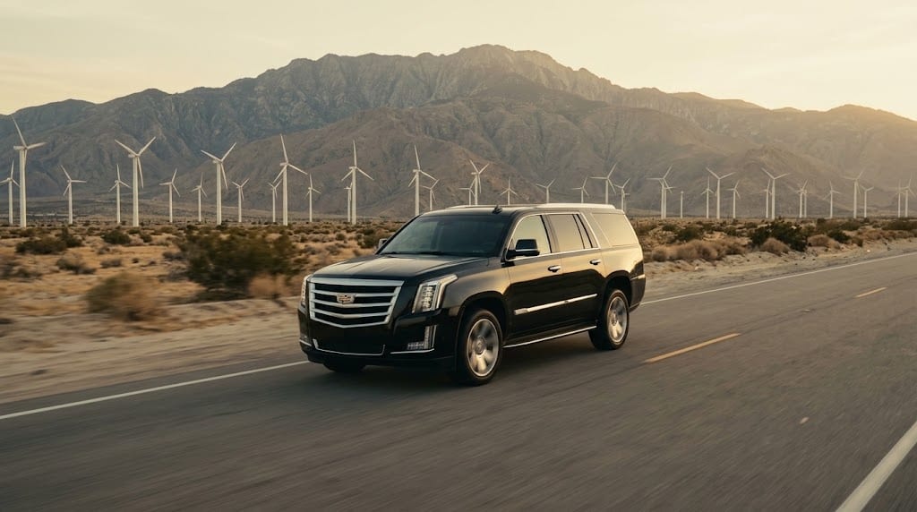 A black SUV on the desert highway near Palm Springs, wind turbines behind